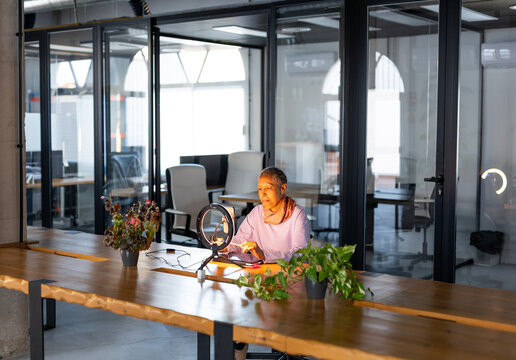 A MATURE WOMAN USING THE PHONE TO MAKE A VIDEO CONFERENCE