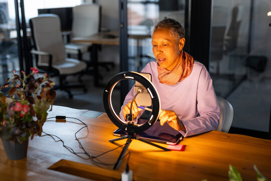 A MATURE WOMAN USING THE PHONE TO MAKE A VIDEO CONFERENCE