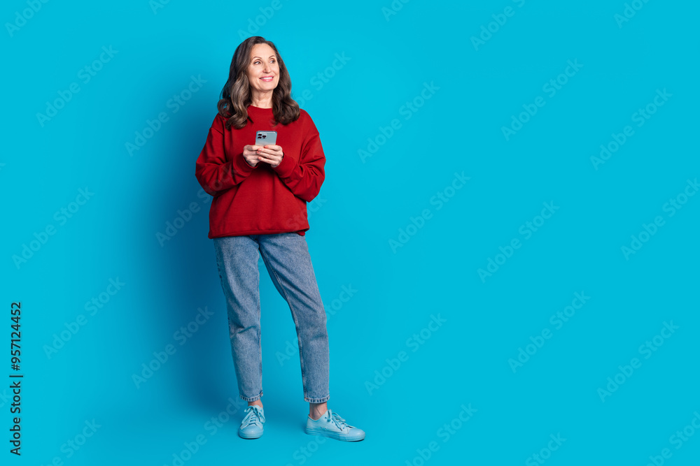 Wall mural full size photo of pretty aged lady hold phone look empty space wear pullover isolated on blue color