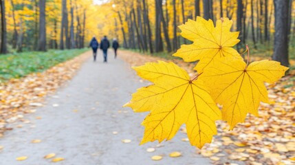 Golden yellow leaves stand out in a park as people leisurely stroll along a blurred pathway, enjoying a beautiful autumn day in nature