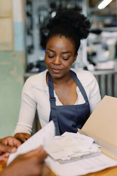 Waitress and partial black male cafe owner checking payments and bills