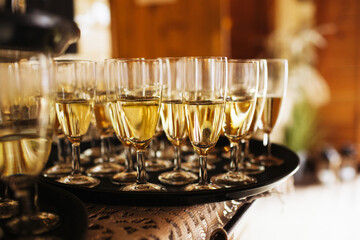 Golden champagne glasses. Tray welcoming guests at a wedding banquet. Celebration, joy, and fine alcohol for a festive event. Shiny alcohol glass. Rustic wedding venue. Planning a party.