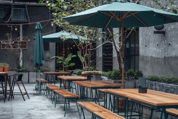 An outdoor cafe with green umbrellas and wooden tables stands ready for customers in a cozy corner with a relaxed atmosphere.