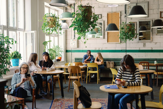 Group of multiracial people resting and enjoying time together in cafe