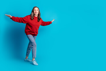 Full size photo of pretty aged lady walk empty space arms wings wear pullover isolated on blue color background