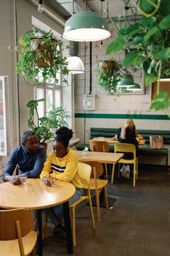 Sad black couple drinking alcohol and girl friends resting in cafe