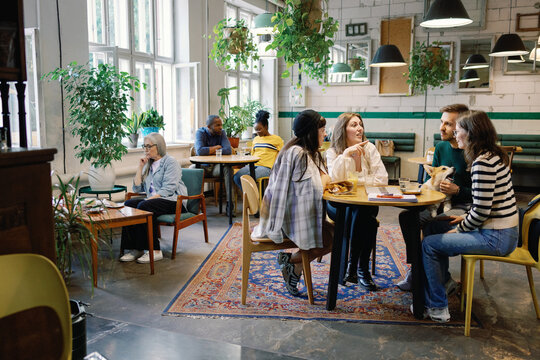 Group of multiracial people resting and enjoying time together in cafe