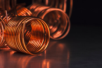 Coils of copper wire close-up on metal surface with dark background
