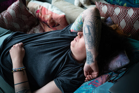 A young tattooed woman resting on couch