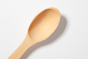 Top view of wooden spoon with shadow, on light background