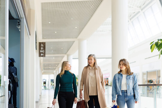 Grandmother, mother and daughter with bags walking in modern mall