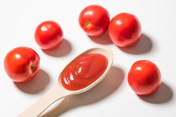Tomatoes and a spoonful of ketchup on a white background, close up
