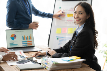 Confident Businesswoman Leading the Way: A young Asian professional radiates confidence as she navigates data and analytics in a dynamic meeting, exemplifying leadership and expertise. 