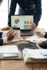 Strategic Business Analytics:  A team huddles over financial data, collaborating on a laptop with...