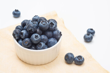 Bowl of fresh blueberries on a light background, close-up. Organic fruits