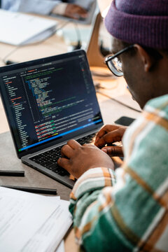 A man is programming on a laptop in the office