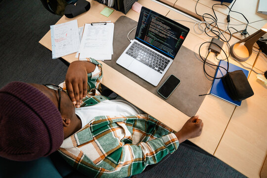A man is programming on a laptop in the office