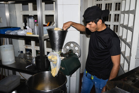 Kitchen worker putting corn into a grinder
