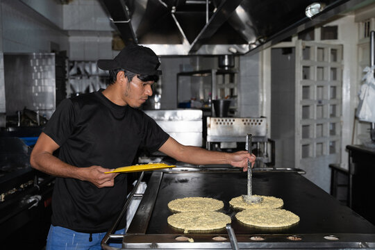 A chef putting cachapa dough on the griddle