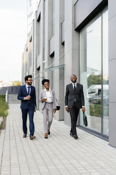 Businessman walking with business associates past corporate building