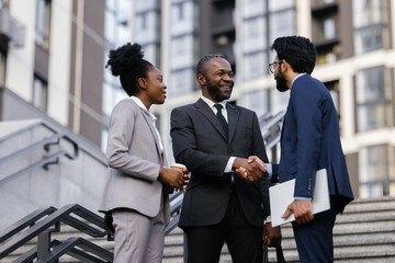 Office manager shaking hands with business partner outdoors