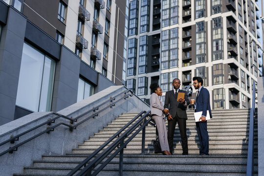 Manager showing something on tablet screen to employees outdoors