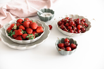Fresh summer berries into bowls on white table. Summer food concept. Soft focus
