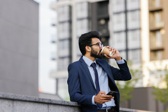 Elegant young businessperson drinking coffee outdoors