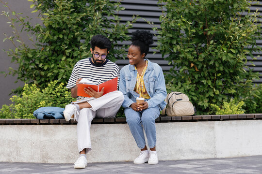 Serious teacher checking homework of student outdoors