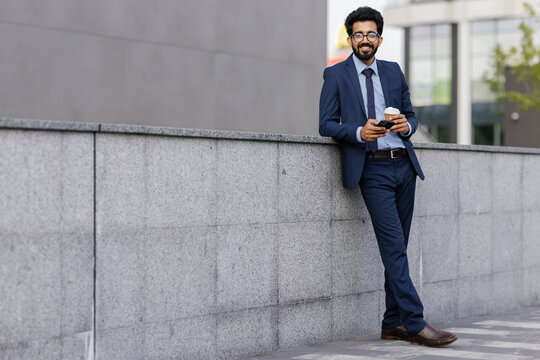 Entrepreneur leaning back against concrete parapet wall during coffee