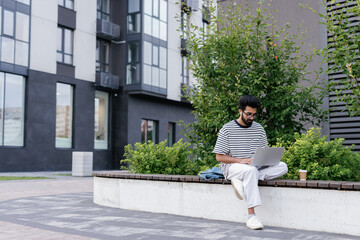 Calm focused web developer working on laptop outdoors