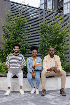 Coworkers and boss posing for camera outdoors during informal meeting