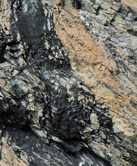 Layered Geological Rock Formation with Contrasting Colors. Layered Rock. Black and orange rock. Rock texture.