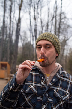 Man eating a maple taffy in the woods