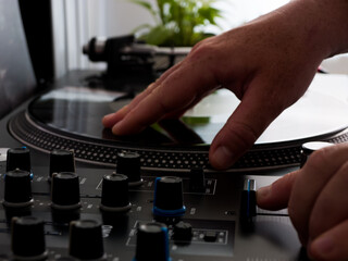 Una mano humana manipulando una mesa de mezclas de deejay.