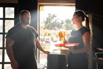 A young waitress serves beer