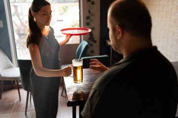A young waitress serves beer