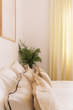 A cozy bedroom scene featuring a neatly made bed and beige pillows