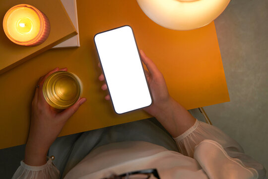 Hand hold smartphone with an empty screen, notebook and tea cup