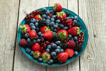Mix of ripe colorful berries in bowl photography . Blueberry , strawberry , raspberry , blackberry and red currant . Top view