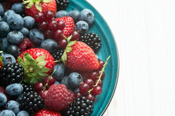 Mix of ripe colorful berries in bowl photography . Blueberry , strawberry , raspberry , blackberry and red currant . Top view