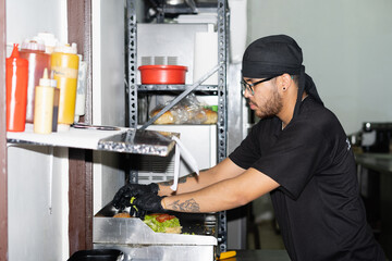 A man placing ingredients on a hamburger bun