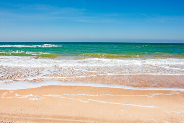 view of ocean waves rolling in sand beach sunny day