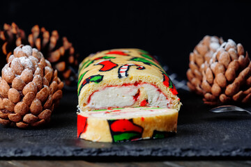Trendy desserts: sliced roll with traditional Christmas patterns, chocolate cakes shaped pine cones on black board, wooden table, black background. Side view. Close up.