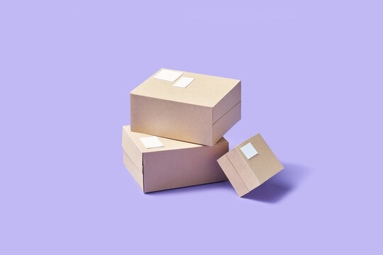 Three cardboard boxes placed chaotically over purple studio background
