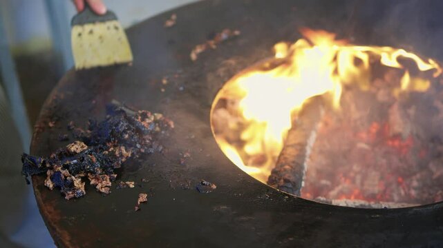 Enjoying grilling in the backyard and using a scraper to clean off burnt residue from the fire pit