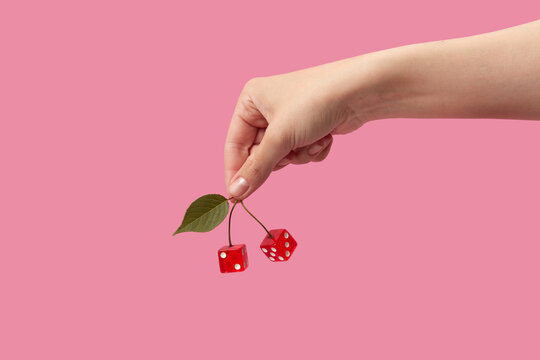 Hand of woman holding stems with dices instead of cherries