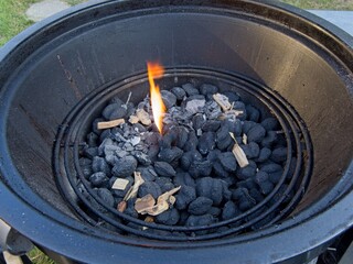 Charcoal with wooden chips is being lit up on the grill
