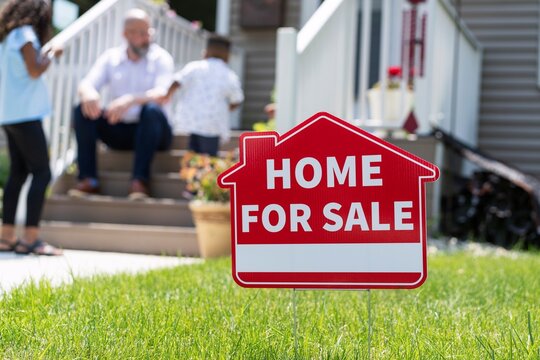 For Sale Sign in Front Yard with Family in Background