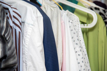 A diverse collection of neatly arranged shirts hangs on a clothing rack in a well-organized closet